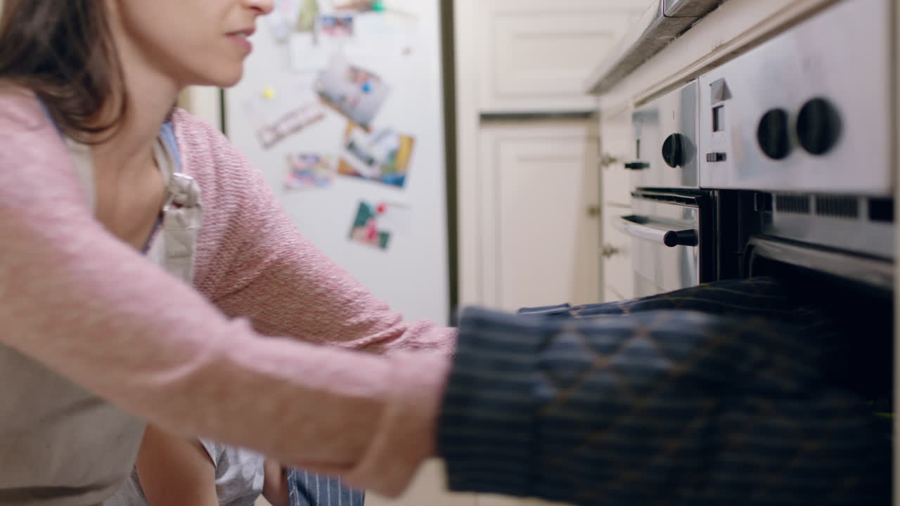 madre e figlia che cucinano in cucina godendosi l'aroma di biscotti appena cotti fuori dal forno indossando guanti da forno piccola ragazza che aiuta la mamma nel fine settimana