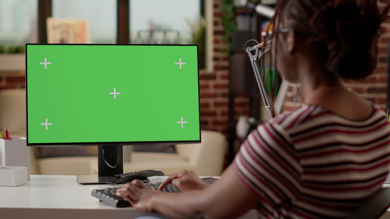 Woman working on computer with green screen