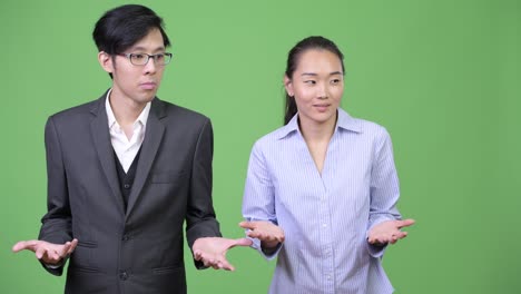 young asian business couple looking guilty together