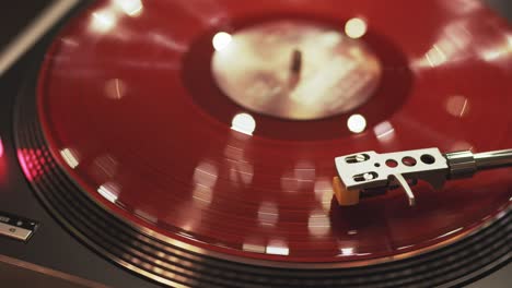 vinyl player on a sunset background with a bokeh lights of the evening city. the girl's hand places the needle on a rotating red vinyl plate. included gramophone and rotating plate