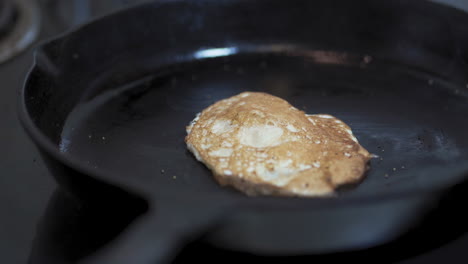 Spatula-flipping-a-seasoned-fried-egg-in-a-cast-iron-skillet