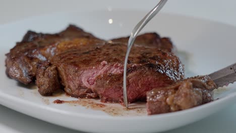 primer plano de entrecote cocido terminado en una placa blanca