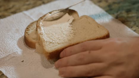 close up spreading cream to a piece of bread