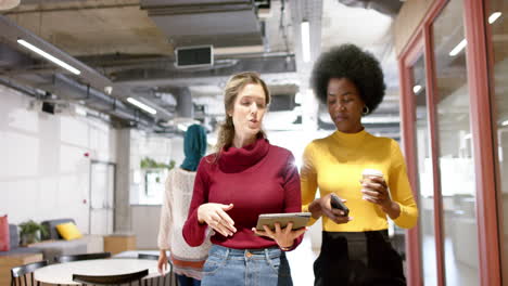 Happy-diverse-female-creative-colleagues-in-discussion-using-tablet-in-office,-slow-motion