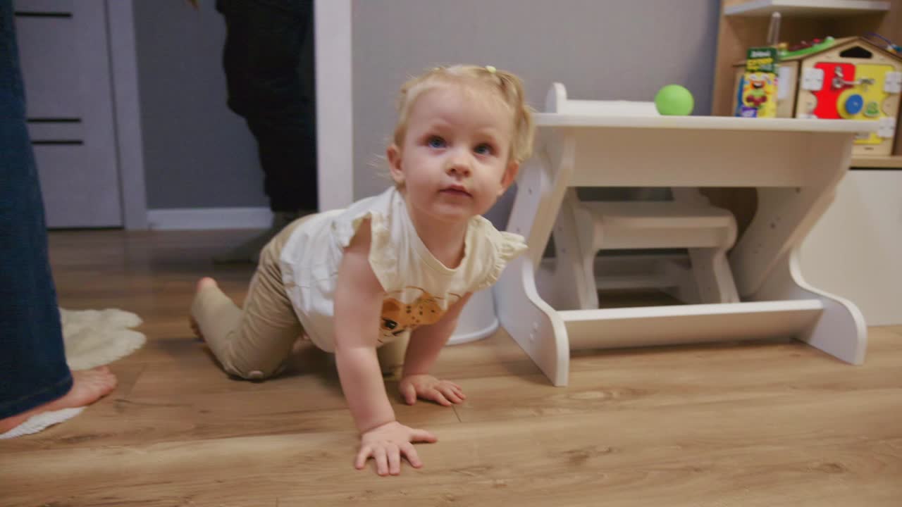 Bambina curiosa in posizione gattonante su pavimento in legno