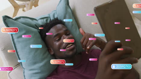 Animation of social media icons over african american man having a video call on tablet at home
