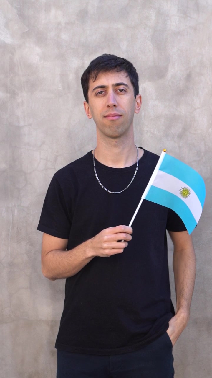 Vertical shot of a man waving Argentine flag in slow motion. Argentina country flag.