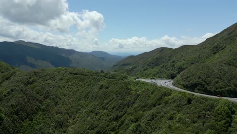 a drone shot of a road that winds through a lush green plant covered hill