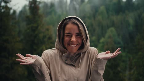Happy-blonde-girl-rejoices-in-the-forest-rain-in-the-mountains-having-fun-and-looking-at-the-camera