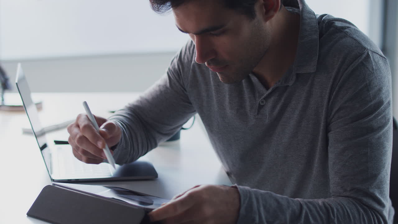 Businessman Working On Laptop At Desk Using Digital Tablet And Stylus