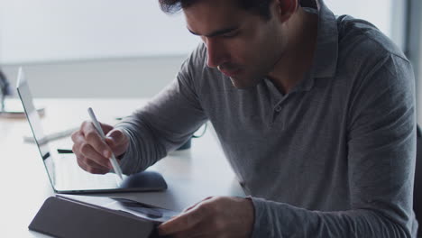 Businessman Working On Laptop At Desk Using Digital Tablet And Stylus