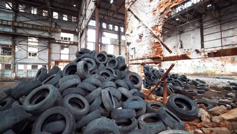 old broken-down building inside with many tires on a large bunch. black used rubber tires of vehicles on a desolate plant