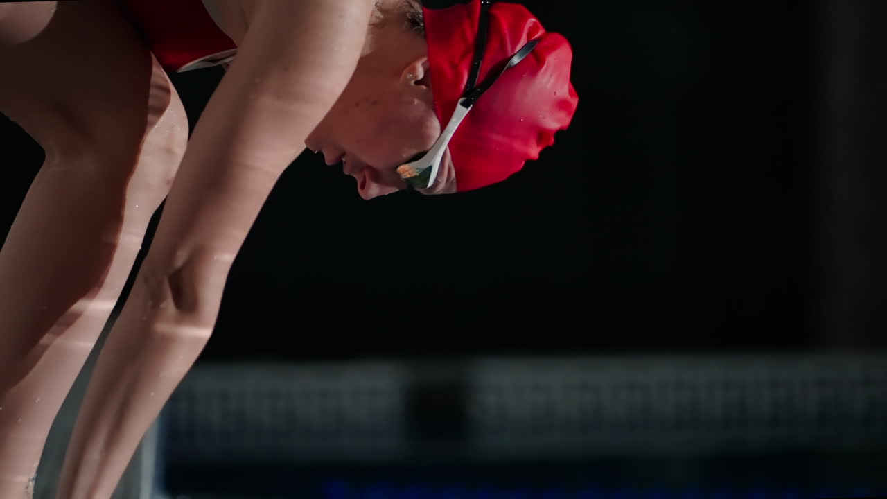 여자 수영 선수가 대회를 위해 수영장에 뛰어들려고 준비하고 있습니다.