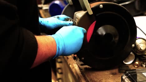 a technician cleans parts on an abrasive wheel