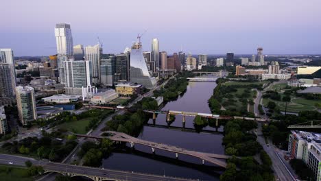 Aerial-view-overlooking-a-cargo-train-arriving-in-Austin,-summer-dusk-in-Texas,-USA