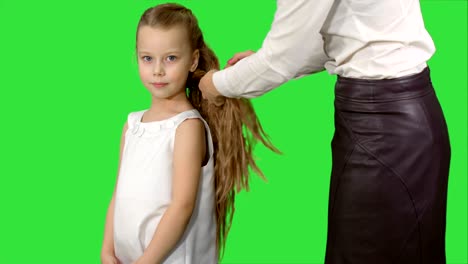 la madre hace el peinado de la hija en una pantalla verde, clave de croma