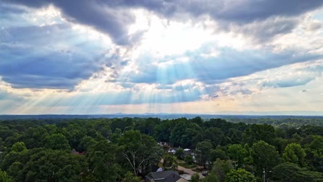 breathtaking drone shot of rays of sun streaking through the clouds in a quaint neighborhood of greenville, sc.