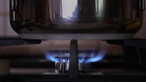 Side-view-woman's-hand-lights-up-the-kitchen-burner-with-pot-on-the-gas-stove