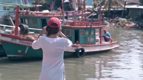 girl with dark hair and smartphone against fishing boats