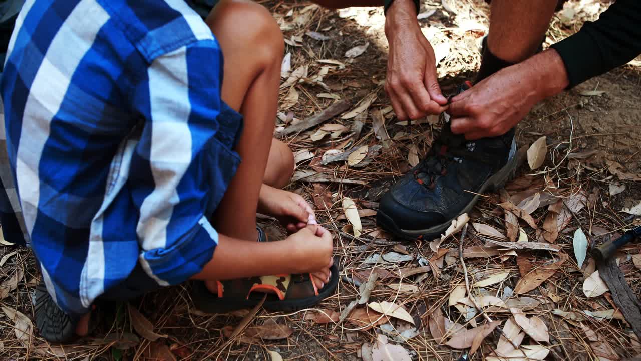 hijo ayudando a su padre a atar el cordón de sus zapatos en el parque
