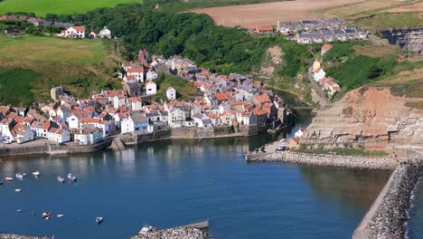 aerial drone view of staithes harbour on the north yorkshire coast with river,houses, boats on a sunny morning in august, summertime