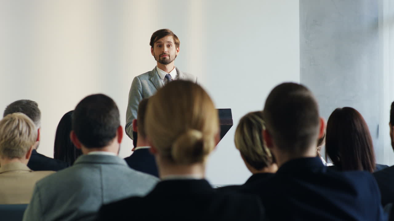 Caucasian businessman wearing formal clothes speaking at a conference in front of many people