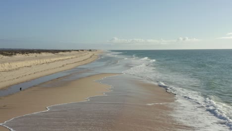 Waves-crashing-in-towards-beach-on-deserted-island-in-Portugal,-golden-sand-as-far-as-the-eye-can-see