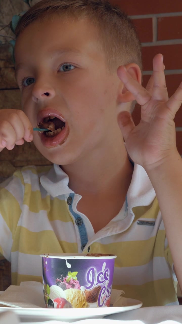 Kid eating chocolate ice cream dessert in summer cafe
