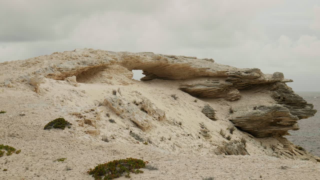 A breathtaking view of a natural rocky arch formation, set against a clear blue sky, highlighting the unique geological features of the landscape.