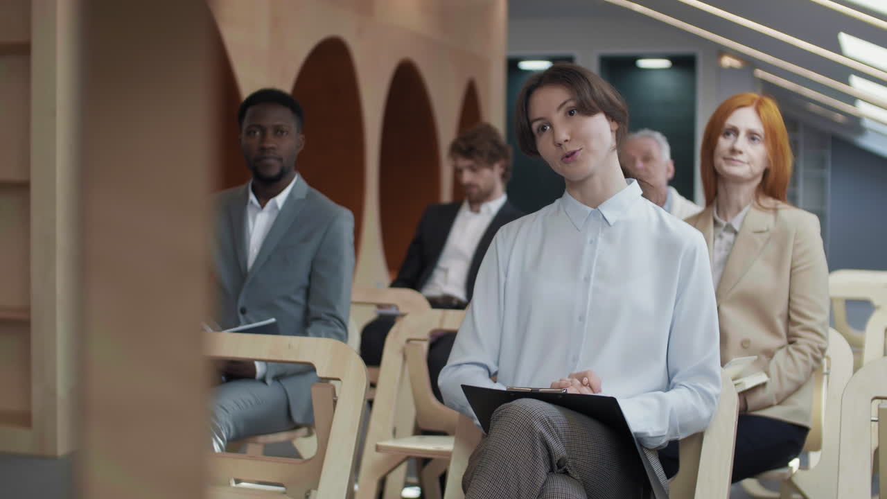 портрет молодой женщины, задающей вопрос на пресс-конференции