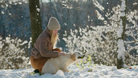 the owner of the puppy strokes her, they walk together in a snowy park