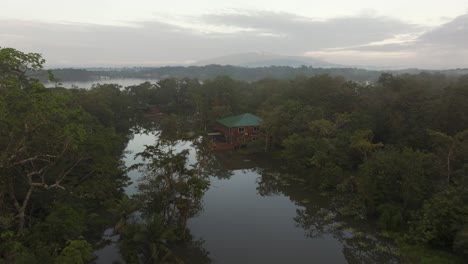 Low-flying-over-wooden-houses-on-dulce-river-at-Guatemala,-aerial