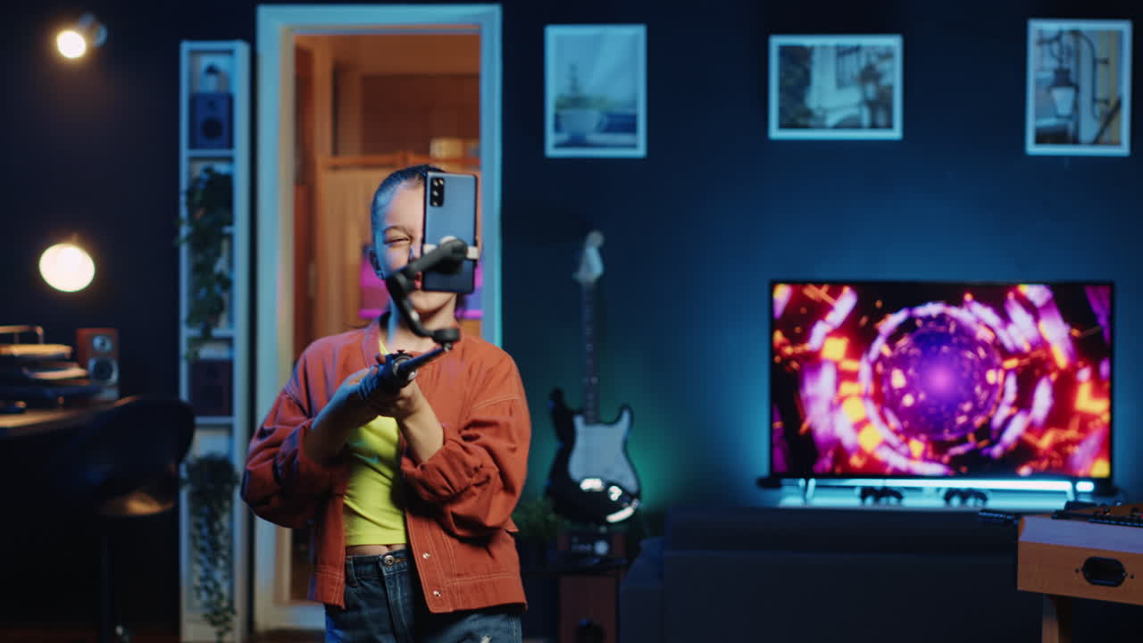 셀카 스틱에 연결된 스마트 폰으로 비디오를 촬영하는 바이럴 댄스 트렌드에 참여하는 즐거운 아이