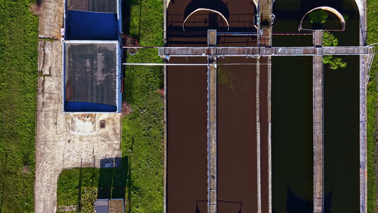 View of a waste management facility with treatment plants located in an open area with grass and pathways visible during daylight hours