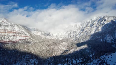 panning drone shot of cloud covered mountain peaks in the winter