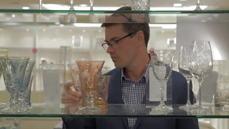 man looking over glassware in the store