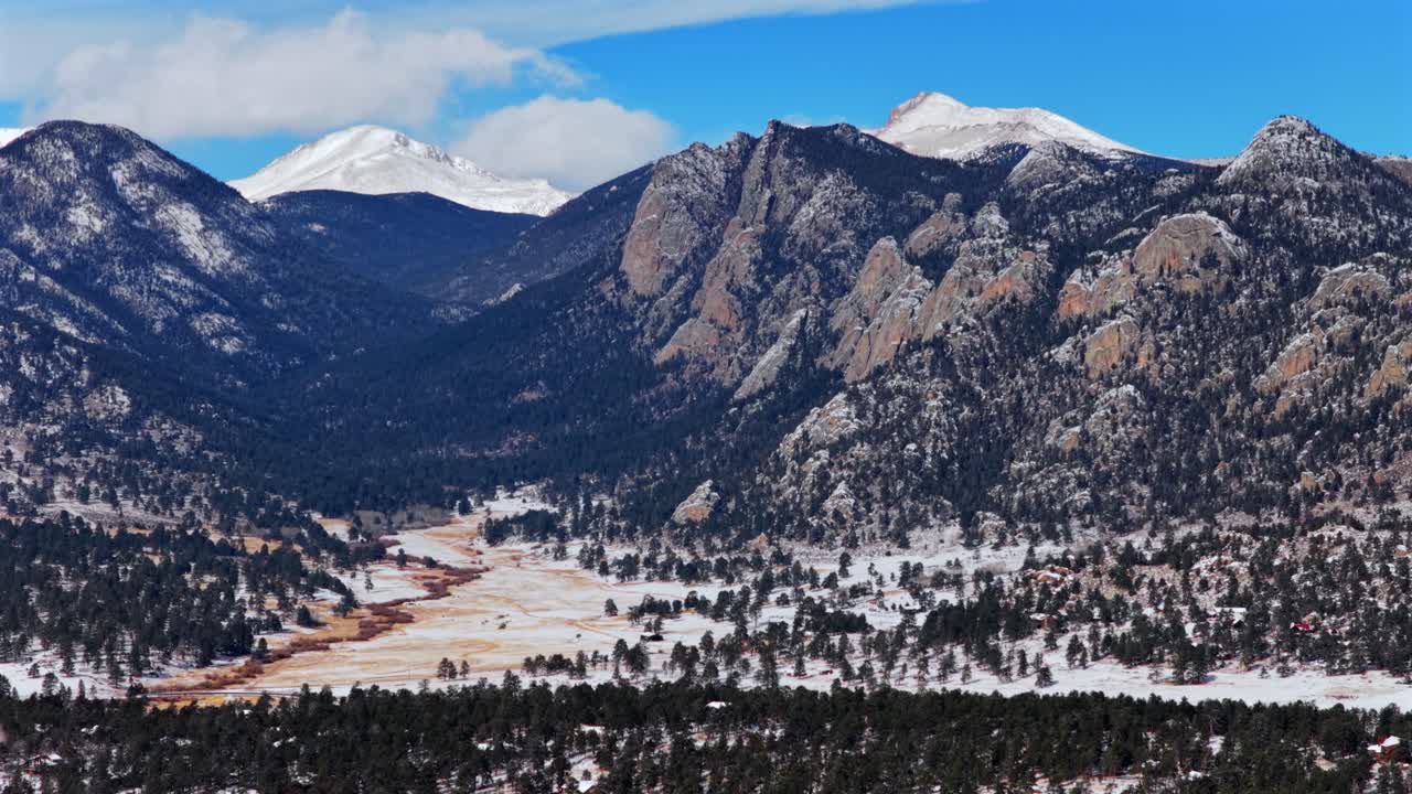 Formazione rocciosa Lumpy Ridge Twin Owls, Catena Mummy Range, Estes Park, Parco Nazionale delle Montagne Rocciose, città di montagna, Colorado. Paesaggio aereo da drone al tramonto pomeridiano, neve fresca, nuvole, cielo blu, soleggiato, in volo circolare verso destra.