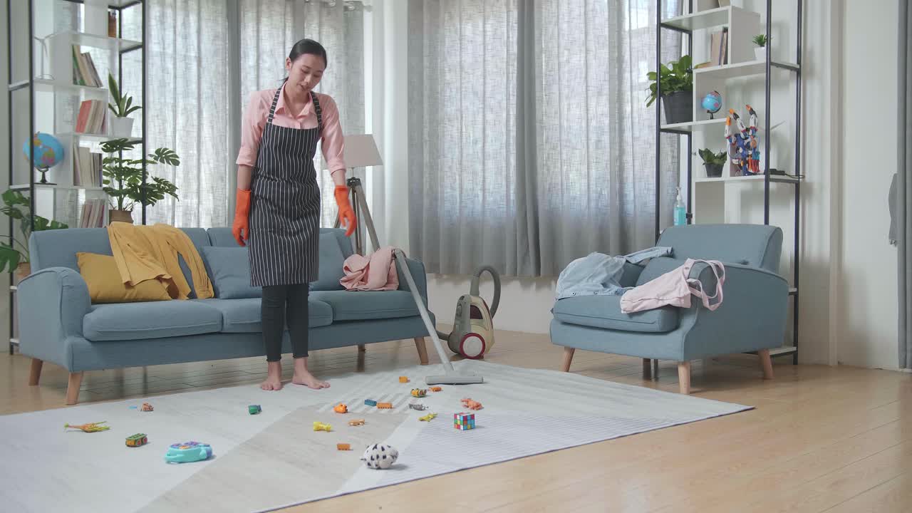 지친 어머니 가 망진창 한 거실 을 청소 하고 있다
