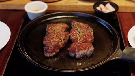 two beefsteak sirloin pieces on meat fried on frying pan in korean restaurant static