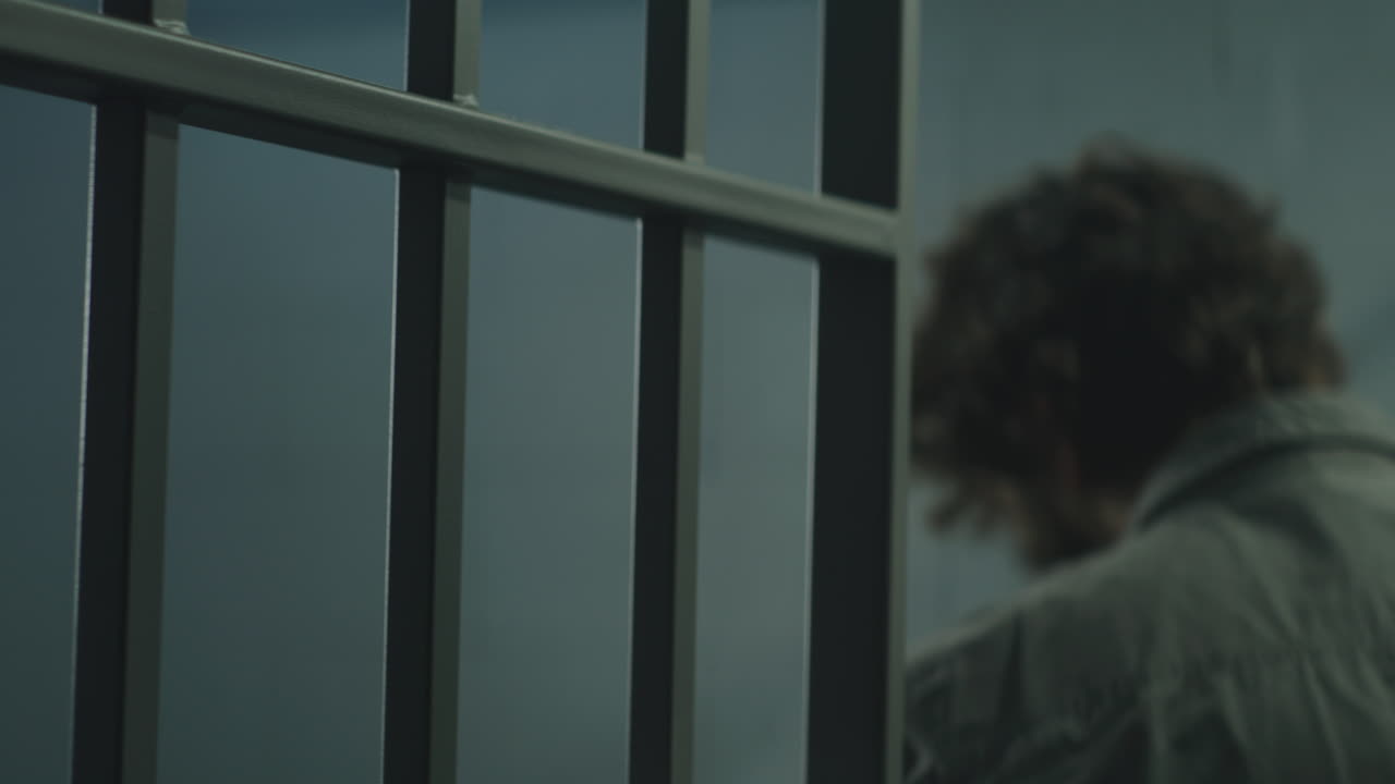 el criminal se encuentra frente a las barras de metal y entra en la celda de la cárcel.