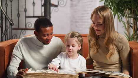 girl steps by fingers on photo album with father and mother