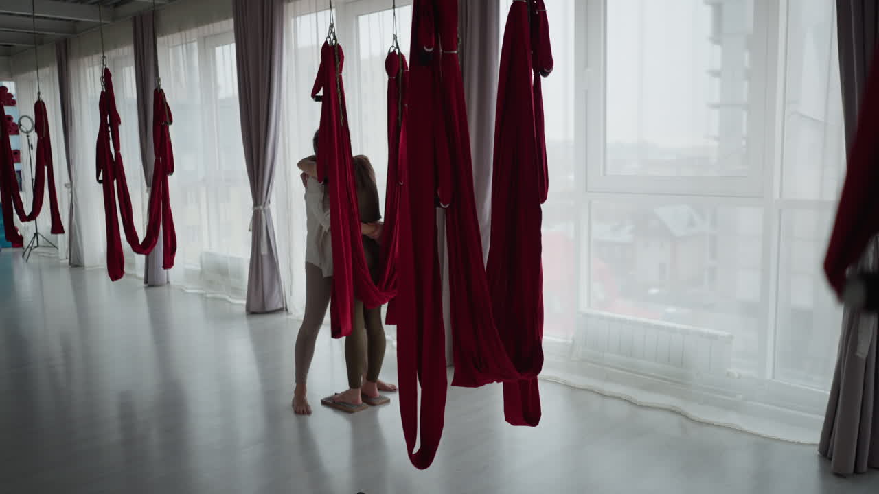 Meditation practitioner embraces partner barefoot on nail board inside calm aerial silk studio under soft natural light expressing support mindfulness trust through healing connection