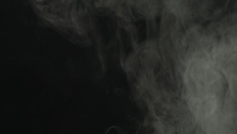 realistic atmospheric gray smoke on black background. white fume slowly floating rises up.