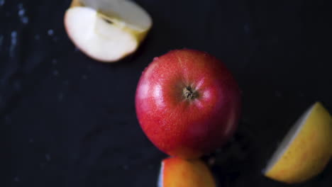 rebanadas frescas de manzana cayendo al agua en pedazos con salpicaduras en cámara lenta