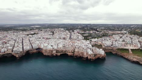 Aerial-panoramic-view-of-Polignano-white-town-on-rocky-cliff-in-Puglia,-Italy