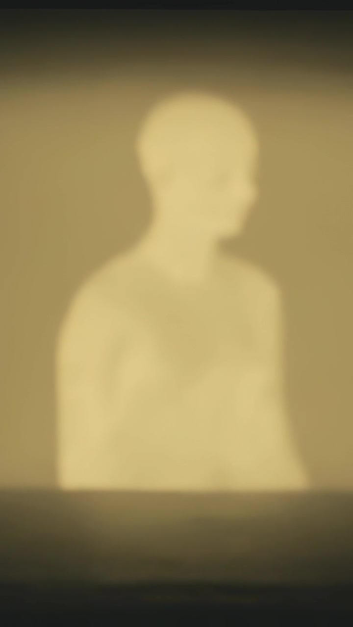Vertical video: Frames showing seated person turning head right in warm studio with low band