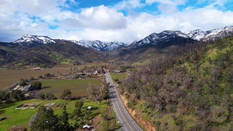 fast aerial glide above napa valley vineyards following a road to snow white mountains