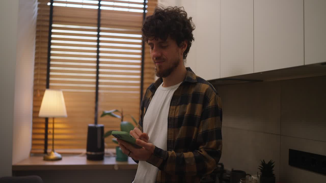 joven usando el teléfono móvil en la cocina moderna