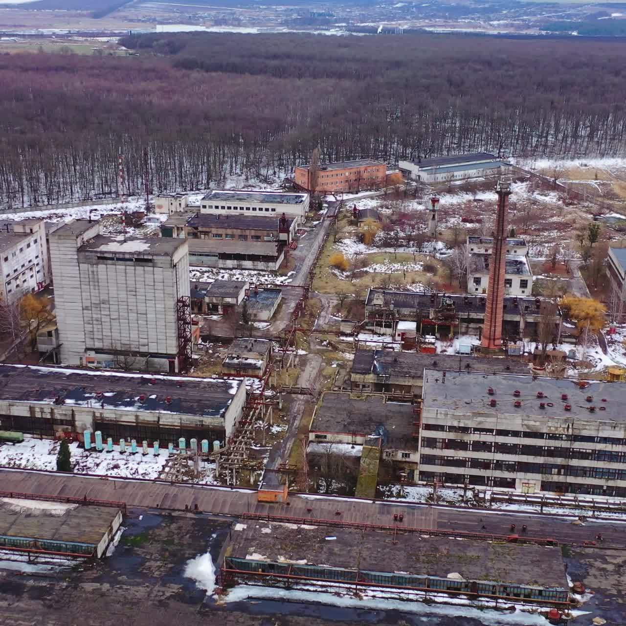 Empty broken industrial plant. Old factory near the forest. Flight over the ruined place after the military actions. Aerial view