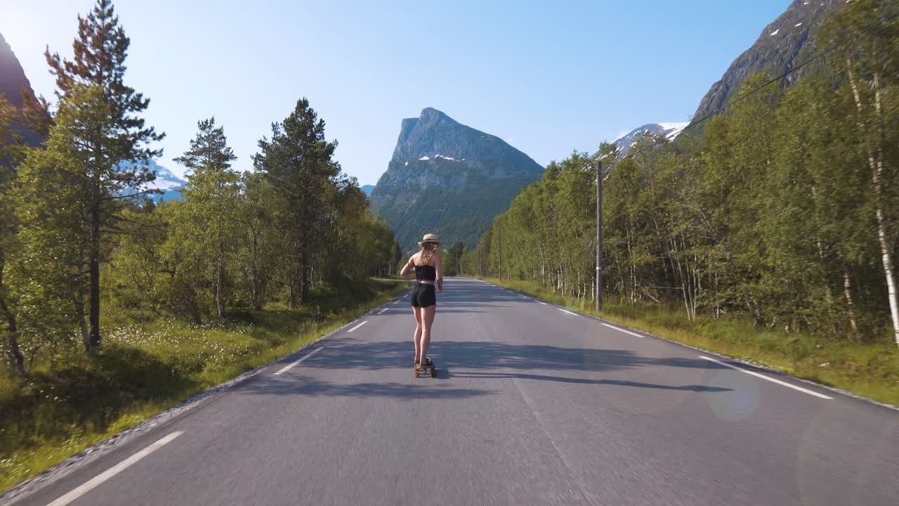 Girl skateboarding down a long road, surrounded by nature environment and mountains in the background, enjoying freedom, Norway.